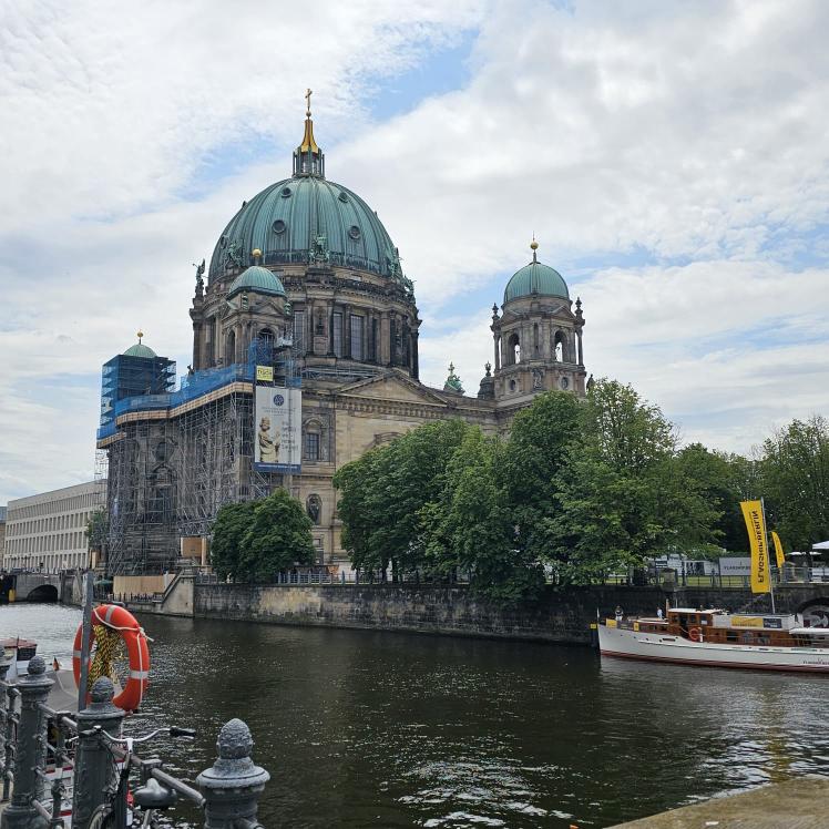 Bick vom linken Ufer über den Fluß, eine Kirche und eine alte kleine Jacht ist zu sehen.